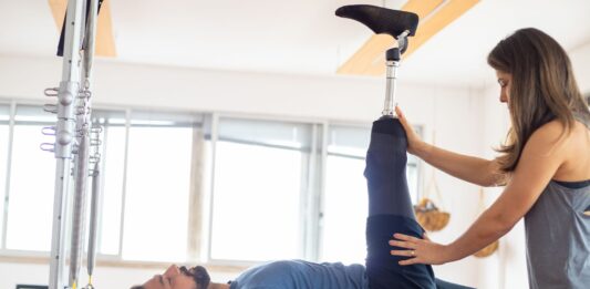 Jak wybrać kurs dla fizjoterapeutów, który realnie podniesie skuteczność terapii w gabinecie Fizjoterapeuta pomaga pacjentowi po amputacji w ćwiczeniach rehabilitacyjnych