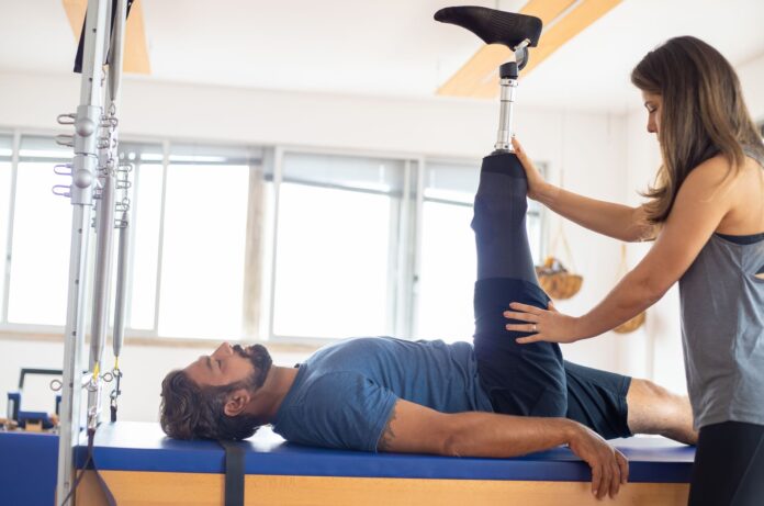 Fizjoterapeuta pomaga pacjentowi po amputacji w ćwiczeniach rehabilitacyjnych