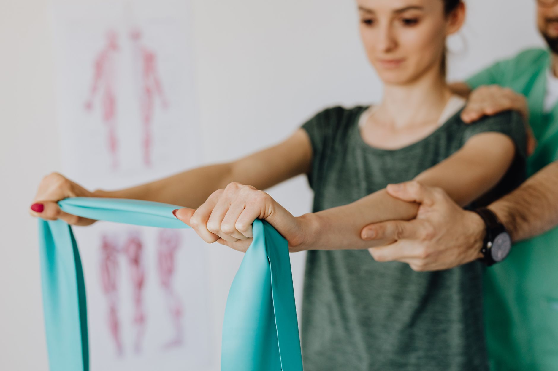 Fizjoterapeuta uczy młodą kobietę ćwiczeń z taśmą oporową w gabinecie