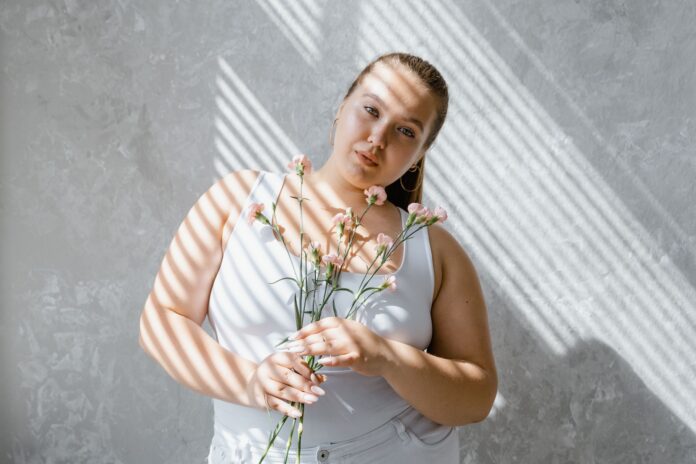 Kobieta plus size w topie na ramiączkach z kwiatami w świetle żaluzji