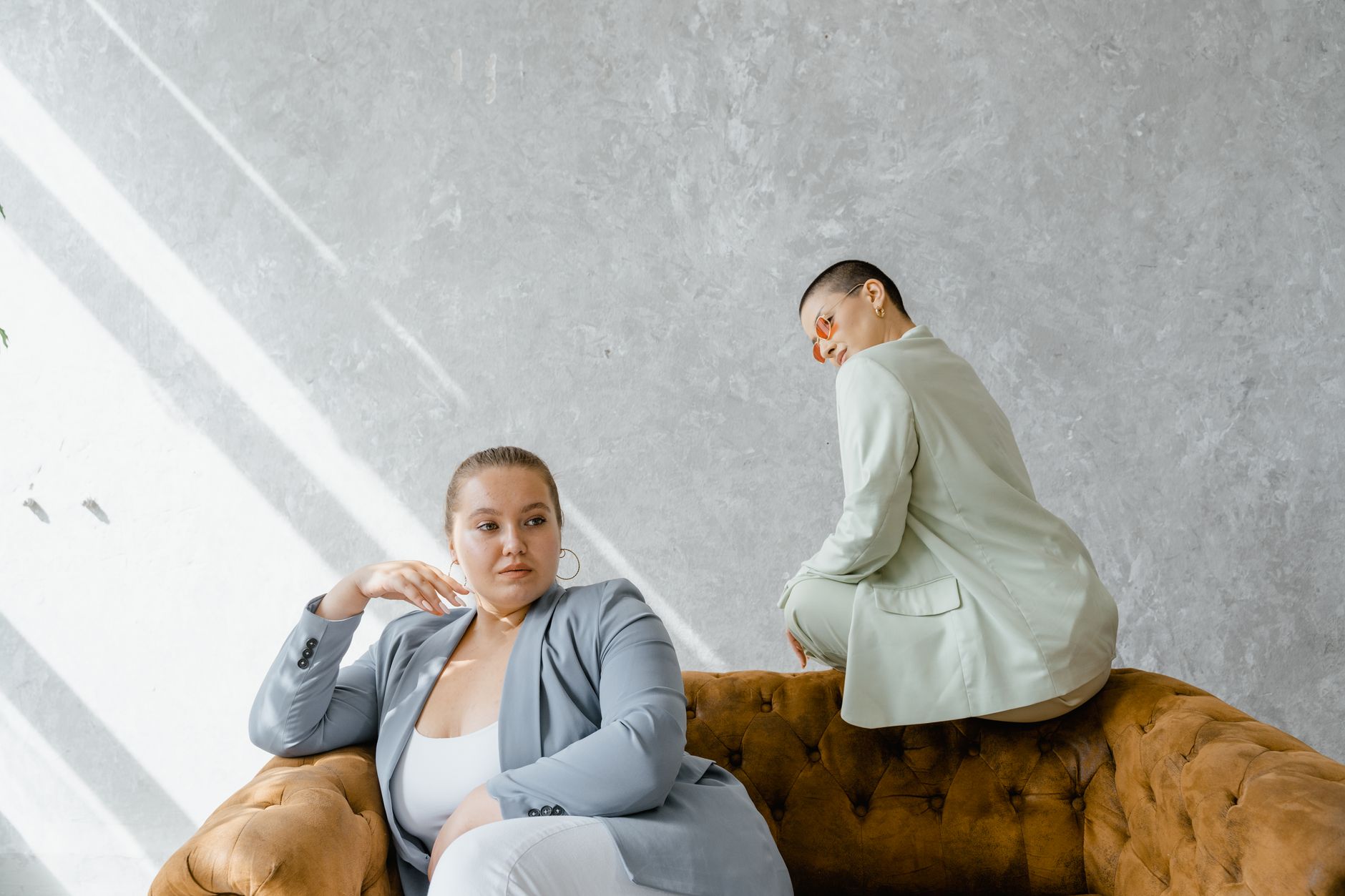 Dwie eleganckie kobiety plus size w garniturach siedzą na kanapie