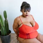 Kobieta body positive w czerwonym stroju kąpielowym obok kaktusa w domu