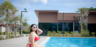Kobieta plus size w czerwonym bikini siedzi przy basenie w okularach