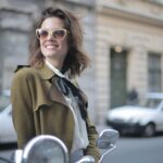 Uśmiechnięta kobieta w eleganckim stroju i okularach na miejskim chodniku